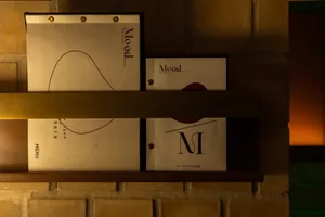 A wooden shelf displays three books arranged in a visually appealing and organized manner