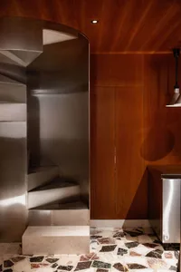 A modern interior design featuring a metal staircase leading to a wooden door, with a focus on functionality and simplicity