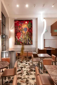溫馨的餐廳內部，牆上掛著大型畫作，配有餐桌與椅子，為客人營造溫暖氛圍