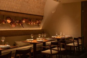 Elegant dining space with multiple tables and chairs, set with wine glasses and cups, creating an inviting atmosphere for fine dining