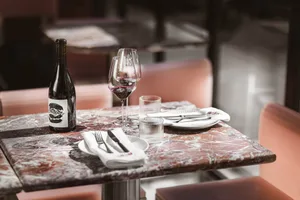 Dining area with a marble table, two chairs, a wine bottle, and wine glasses, set in a sophisticated and inviting environment
