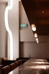 A modern dining space with white walls, illuminated by ceiling lights, and a comfortable atmosphere
