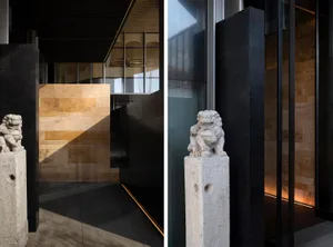 A museum space with a marble statue and stone wall, featuring a staircase and artwork on display