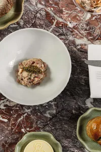 A dining table set in a restaurant with a marble countertop, a white bowl, knives, and a wine glass, creating an elegant and sophisticated atmosphere