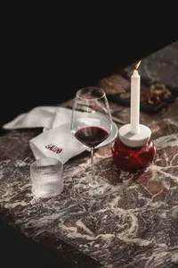 A dining table with marble surface, wine glasses, a bottle of wine, and a cup, set in a cozy and inviting space
