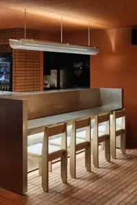 Modern bar with a metallic countertop, stools, and four chairs, creating a comfortable seating area for customers