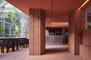 A cozy restaurant interior with red brick walls, a tile floor, and a dining table surrounded by chairs and bottles