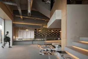 A modern cafe with a large open space, high ceilings, and comfortable seating areas with chairs and a dining table