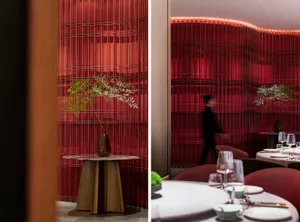 Modern dining space with red walls, a dining table, and vertical stripes on the wall, surrounded by functional furnishings
