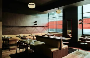 Dimly lit restaurant interior with wooden floors and walls, multiple dining tables and chairs, and a cozy atmosphere