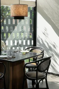 A formal dining area with a large wooden table set for dinner, surrounded by chairs and wine glasses