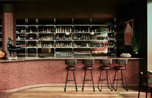 A cozy bar area with a long red counter, stools, and bottles displayed, creating a warm and inviting atmosphere for socializing and enjoying drinks