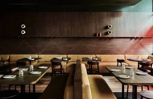 Warm and inviting restaurant interior with wooden walls, tables, and seating areas, featuring comfortable furniture and utensils