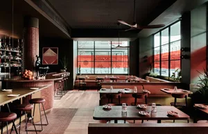 A modern restaurant dining area with multiple tables and chairs, wooden flooring, and well-designed lighting creating a cozy atmosphere