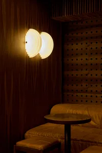 Cozy living space with a couch in front of a wooden wall, lit by two hanging lights