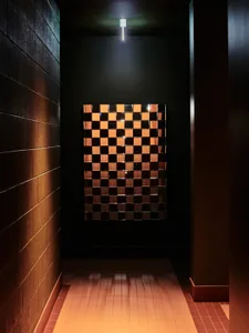 A dark hallway with a mirror reflecting the checkered tile pattern, surrounded by wooden walls and an atmosphere of solitude