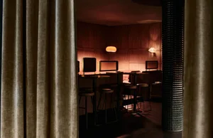 Modern restaurant interior with wooden walls and tables, warm ambiance, multiple chairs, bar, and couches