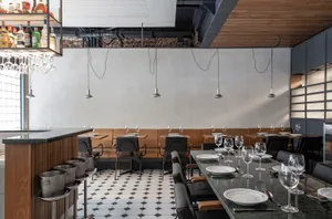 An inviting restaurant interior with a large dining table, wooden chairs, and wine glasses, set for dinner service