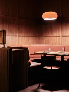 Warm and inviting restaurant interior with wooden walls and tables, featuring table settings and comfortable seating