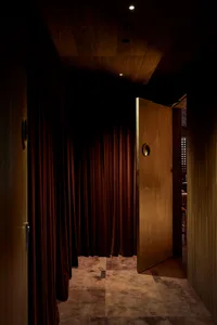 A darkened room with a wooden door and red curtains, creating a cozy atmosphere
