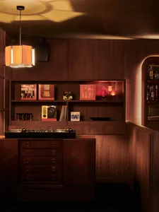 Cozy living space with wooden walls and floors, featuring books, bottles, and a warm atmosphere