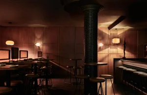 Warm and inviting bar area with wooden walls and floors, featuring chairs and dining tables for guests to socialize and relax