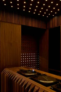Dark wood paneled room with a wooden table and DJ setup, featuring decorative circles on the wall and a warm, cozy atmosphere