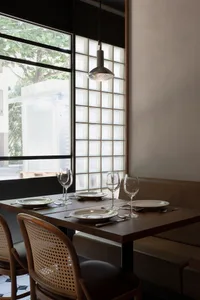 A dining area with a wooden table, chairs, wine glasses, bowls, and cups, set for a meal in a sophisticated and inviting environment