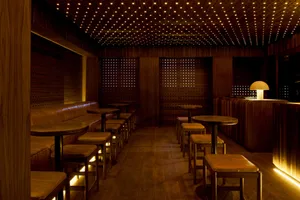 Warm and inviting restaurant interior with wooden floors and walls, featuring multiple tables and chairs, couches, and dining tables