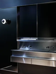 A modern kitchen with two sinks, stainless steel countertops, and dim lighting creating a cozy atmosphere