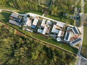 Aerial view of a modern house with multiple stories, featuring a mix of concrete, glass, and wood materials, and ample natural light from numerous windows