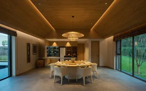 Modern open concept living space with a dining table, chairs, and kitchen area, featuring a refrigerator and oven, with a well-lit and comfortable atmosphere