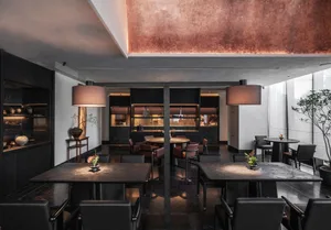 Sophisticated restaurant interior with multiple dining tables, wood paneling, and warm lighting