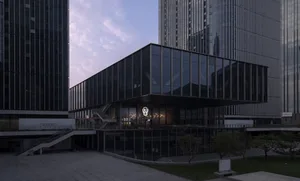 A modern building with a sleek facade featuring glass panels and multiple windows, allowing natural light to enter the interior spaces