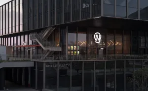 A modern building with a black facade and glass front, housing a water party venue with chairs and a staircase, creating a sophisticated and inviting atmosphere for socializing and entertainment
