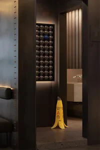 Industrial bathroom with metal walls, a yellow caution cone, and balls hanging from the ceiling, conveying a functional and utilitarian atmosphere