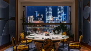 A round dining table surrounded by chairs, with wine glasses and cups, and potted plants adding to the ambiance in an elegant and sophisticated restaurant setting