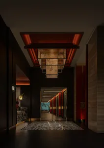 現代飯店走廊，以黑紅色調為主，牆上掛有藝術品，多扇門通往不同房間