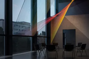 A modern room with glass walls, featuring a semi-circle arrangement of five chairs for a calm and inviting meeting or classroom setting