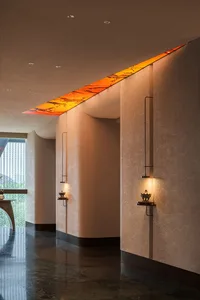 A warm and inviting hallway with orange designs on the walls, lit by three overhead lights