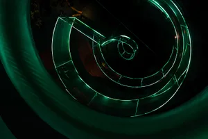 A spiral staircase with green neon lights in a dark, futuristic environment