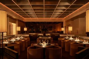 Sophisticated restaurant interior with brown leather chairs, tables, and couches, and wine glasses on some tables