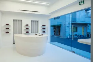 A clean and organized showroom with a round table and chairs, featuring various items on display