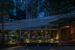 A cozy dining area with a large table and chairs, surrounded by potted plants, in a restaurant setting