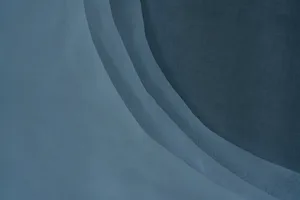 一塊大型白色窗簾呈現摺疊外觀，懸掛於窗前，營造寧靜祥和的氛圍