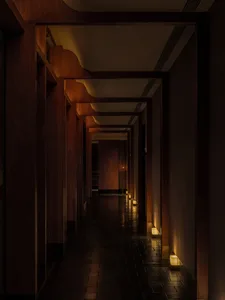 A modern hotel hallway with wooden walls and floors, lit by overhead lights and providing a comfortable atmosphere for guests