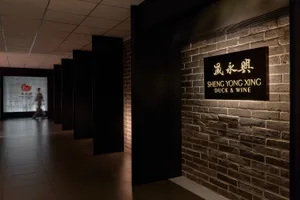 磚牆、石材點綴與黑色門口的優雅亞洲餐廳，門牌寫著「晟永興」與「duck & wine」