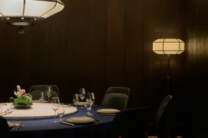 A cozy dining area in a restaurant with a round table set for dinner, surrounded by chairs and wine glasses, creating an inviting atmosphere for guests