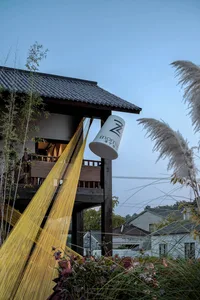A photo of a cozy house with a wooden exterior, featuring a dining table and two chairs, with a white cup hanging on its side