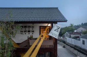 A traditional Asian-style house with a wooden exterior, featuring a balcony with yellow ropes and potted plants inside, creating a cozy and lively atmosphere